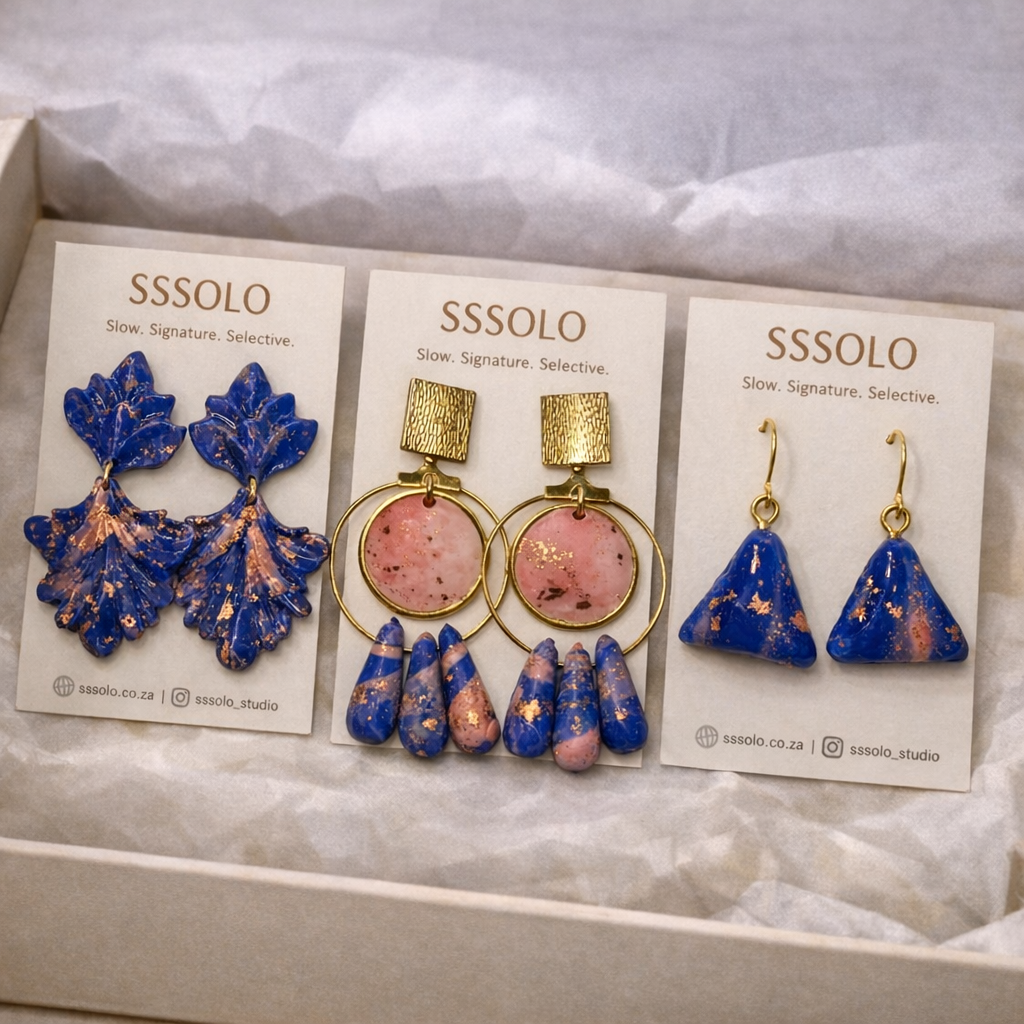 A pink and blue set of 3 earring pairs that follow a similar design, presented as a collection for customers to own. 